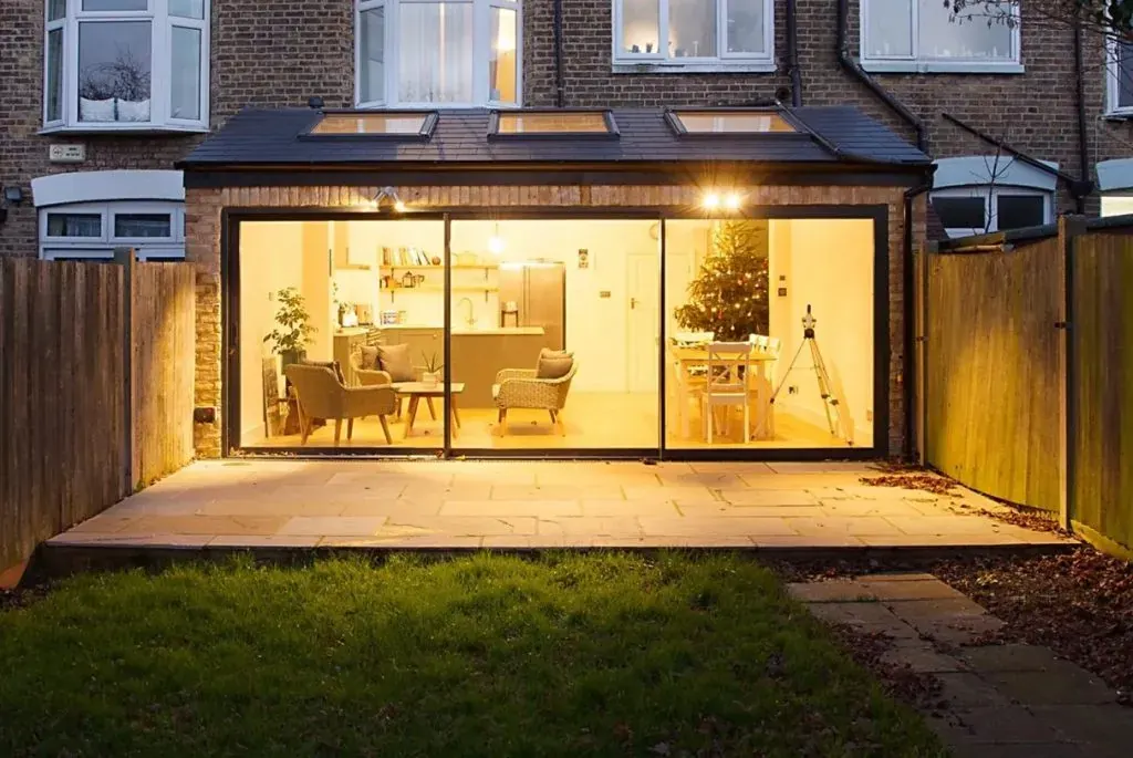 Terraced house rear extension with slimline sliding doors, lit at night, built by ATKINSONS